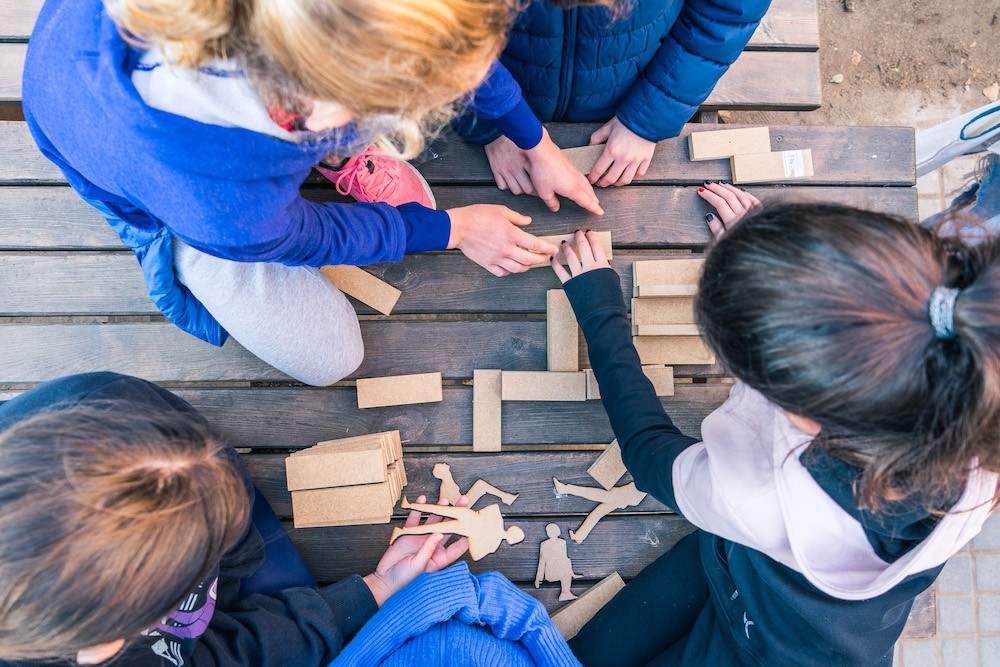 Young students co-design the intervention with scale wood blocks during a workshop before installation.