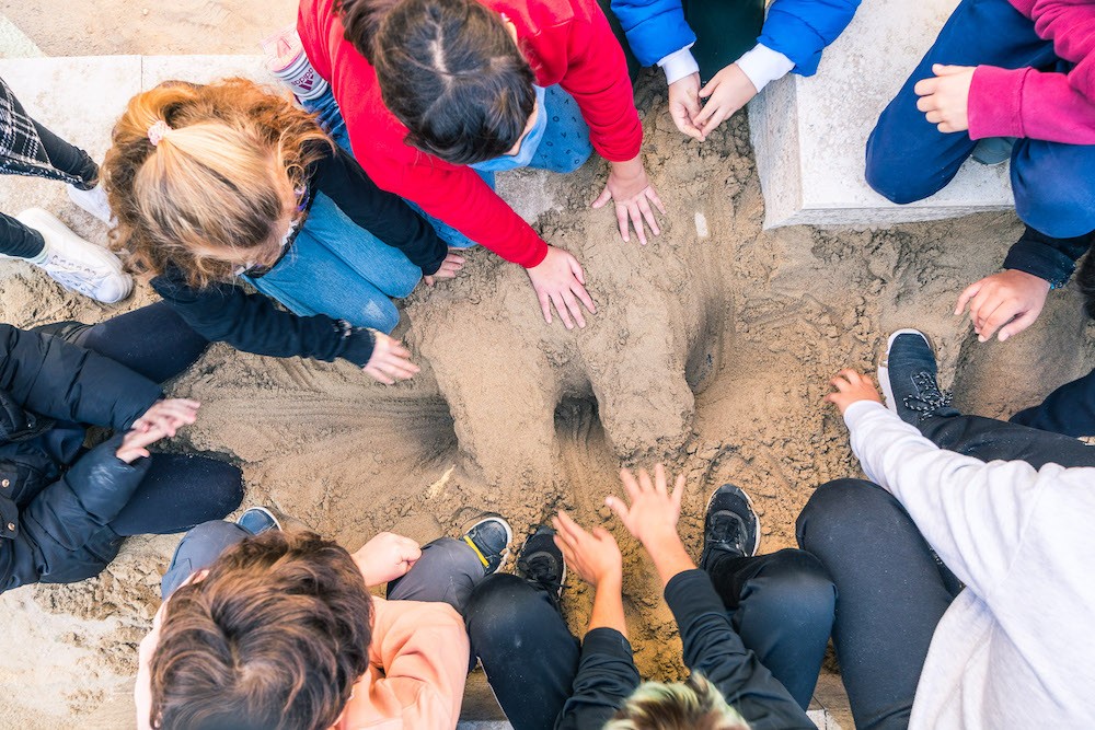 Children digging into the integrated sand-pit portion of the rammed earth play installation.