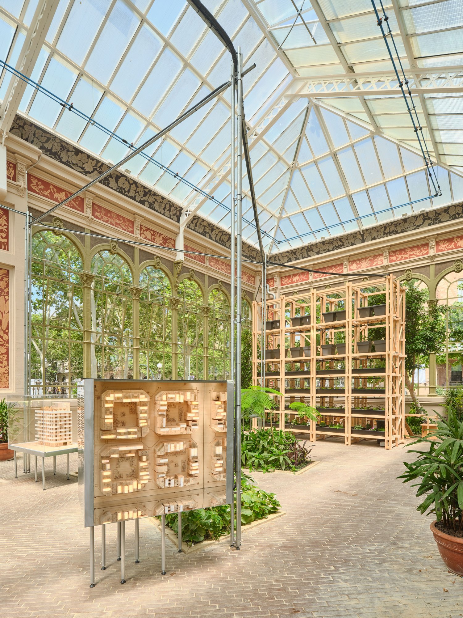 A modular vertical planting system demonstrates the ability to materialize rooftop greenhouses from 0km timber, while models illustrate the potential for replication across the city.