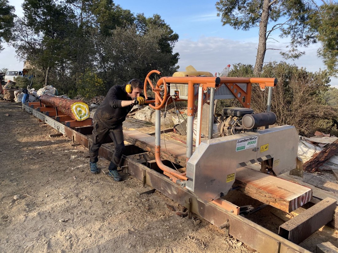 Milling raw timber into structural lumber on site.